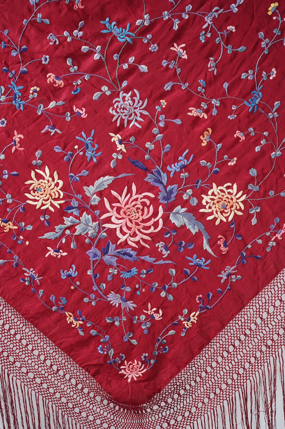 A late 19th early 20th century Chinese silk polychrome embroidered shawl on a maroon silk background. Fringed. 180cm x 60cm. Condition - no fading to colours, silk good